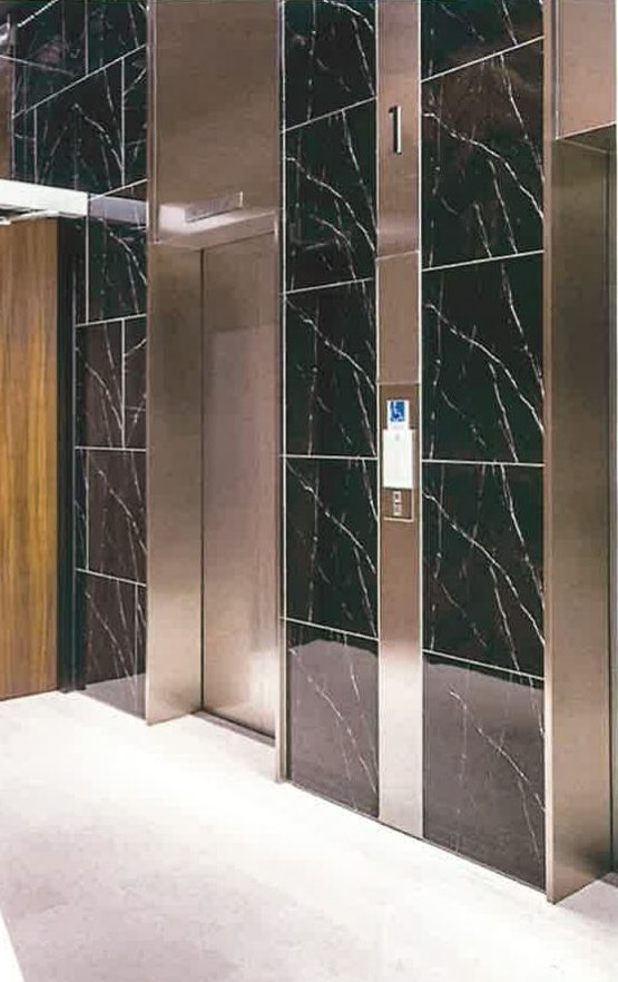 Modern lift lobby with dark marble panels and stainless steel doors